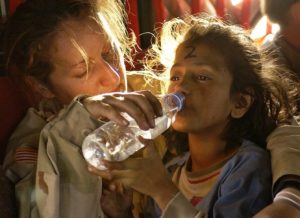Femme qui donne de l'eau a un enfant assoifé