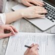 Personne remplissant un formulaire administratif lié à un transfert de propriété immobilière