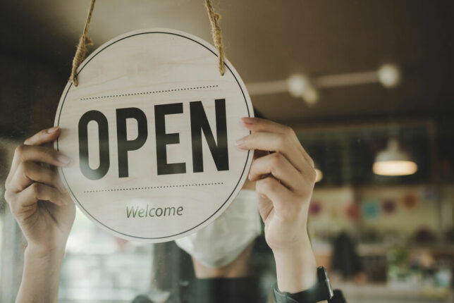 Main tenant le signe "open" d'un magasin