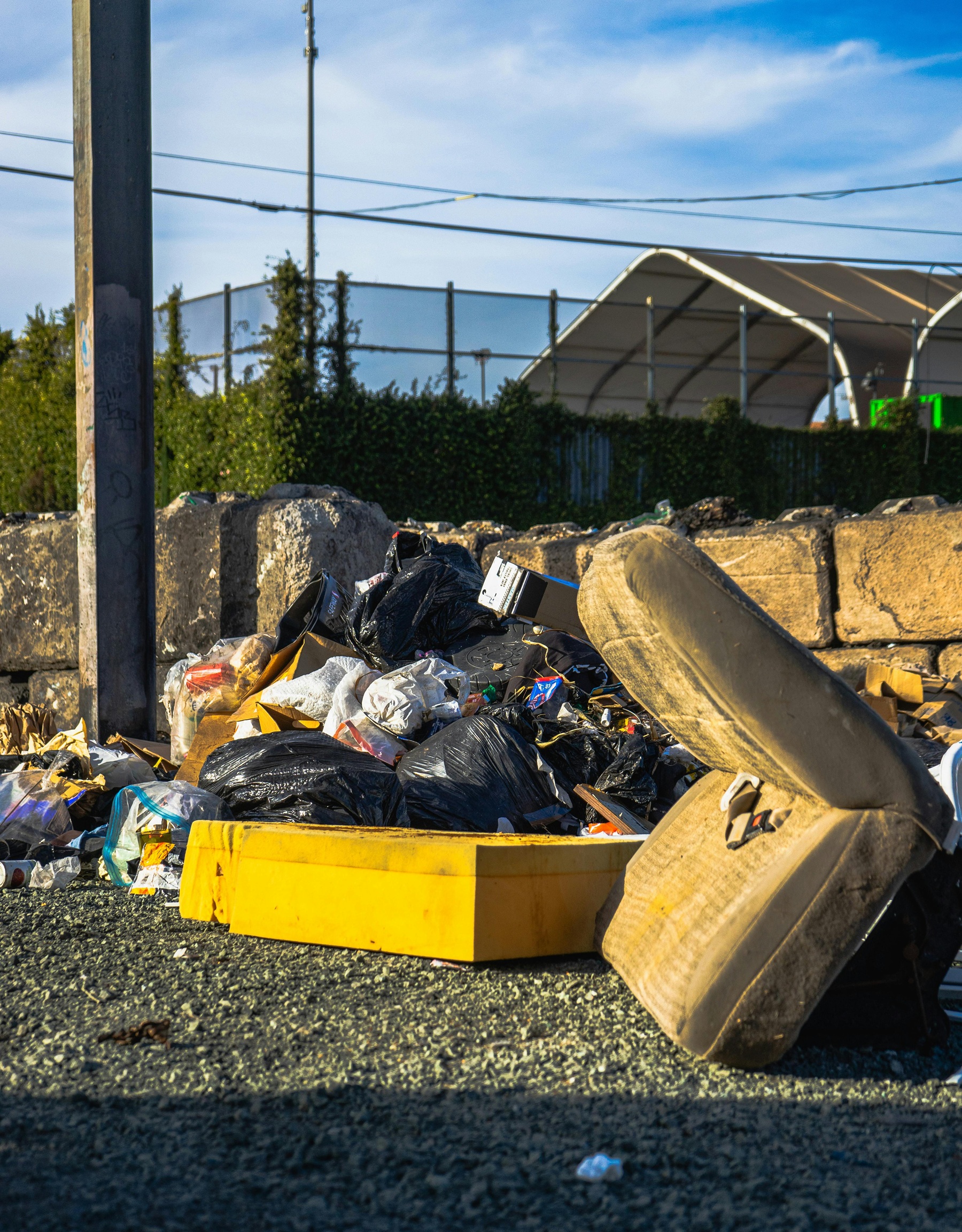 Tas d’encombrants et de sacs-poubelles abandonnés sur la voie publique, illustrant un dépôt sauvage.