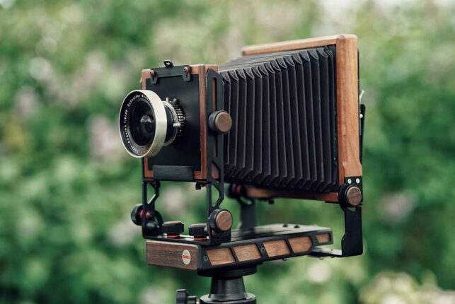 Appareil photo argentique Ondu Eikan avec structure en bois, posé sur un trépied, en extérieur.