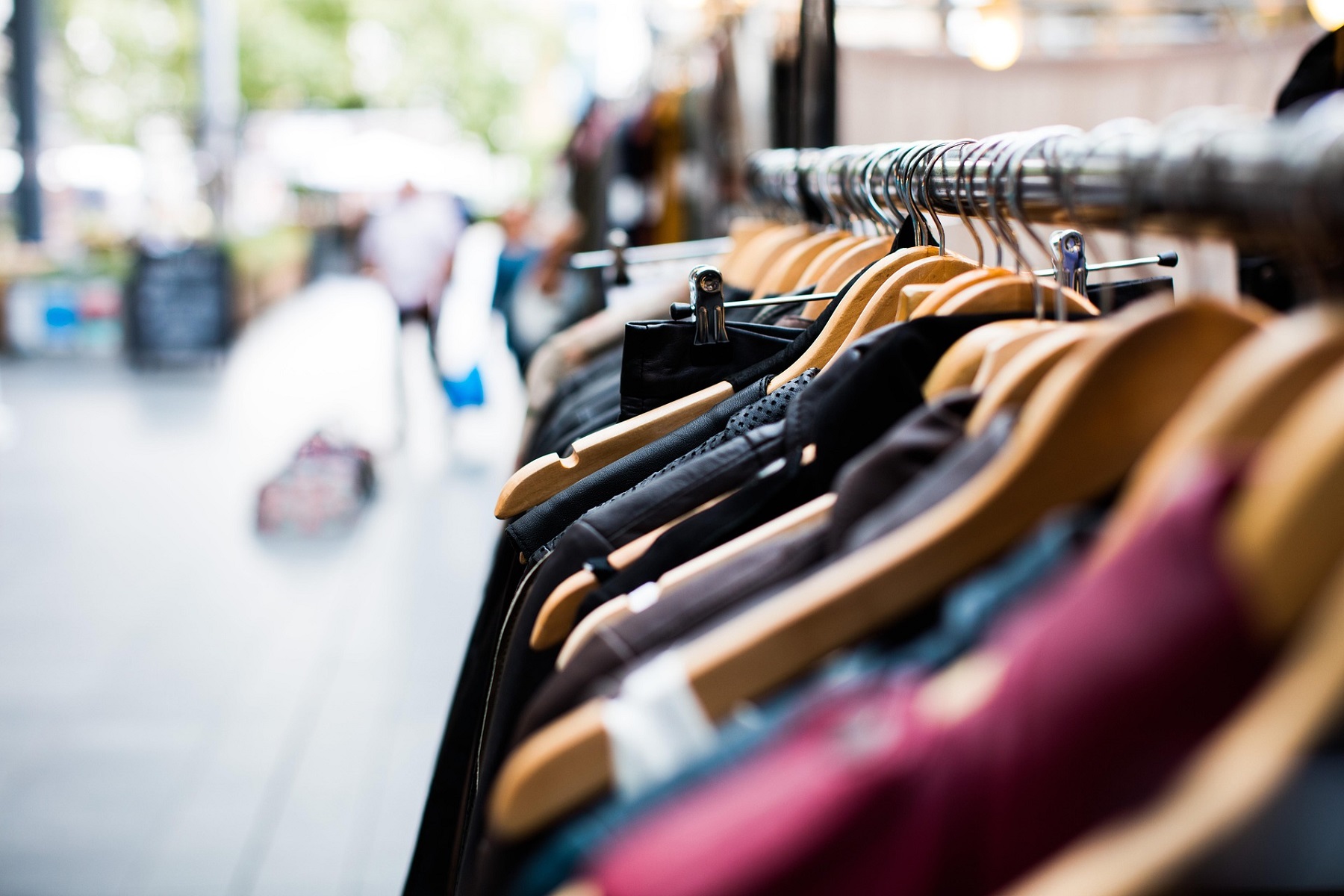 Portant de vêtements sur cintres dans une boutique, avec un arrière-plan flou en extérieur