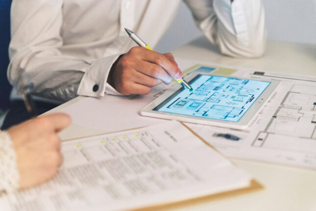 Architectes et ingénieurs analysant une maquette numérique de bâtiment sur tablette