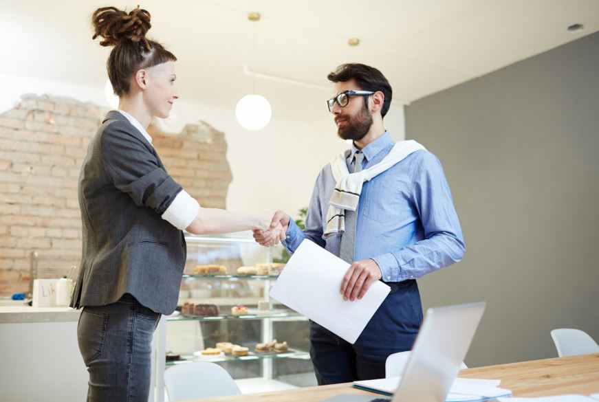 Un homme et une femme se serrent la main pour conclure un accord dans un café