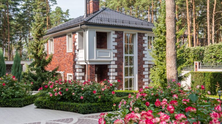 Une grande maison en briques rouges entourée d'un jardin de roses en fleurs