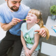 Un père aide sa fille à se brosser les dents dans la salle de bain.