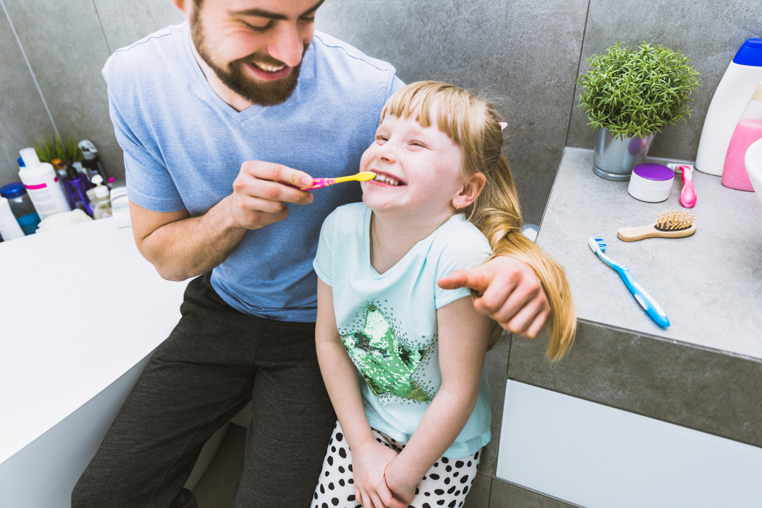 Un père aide sa fille à se brosser les dents dans la salle de bain.