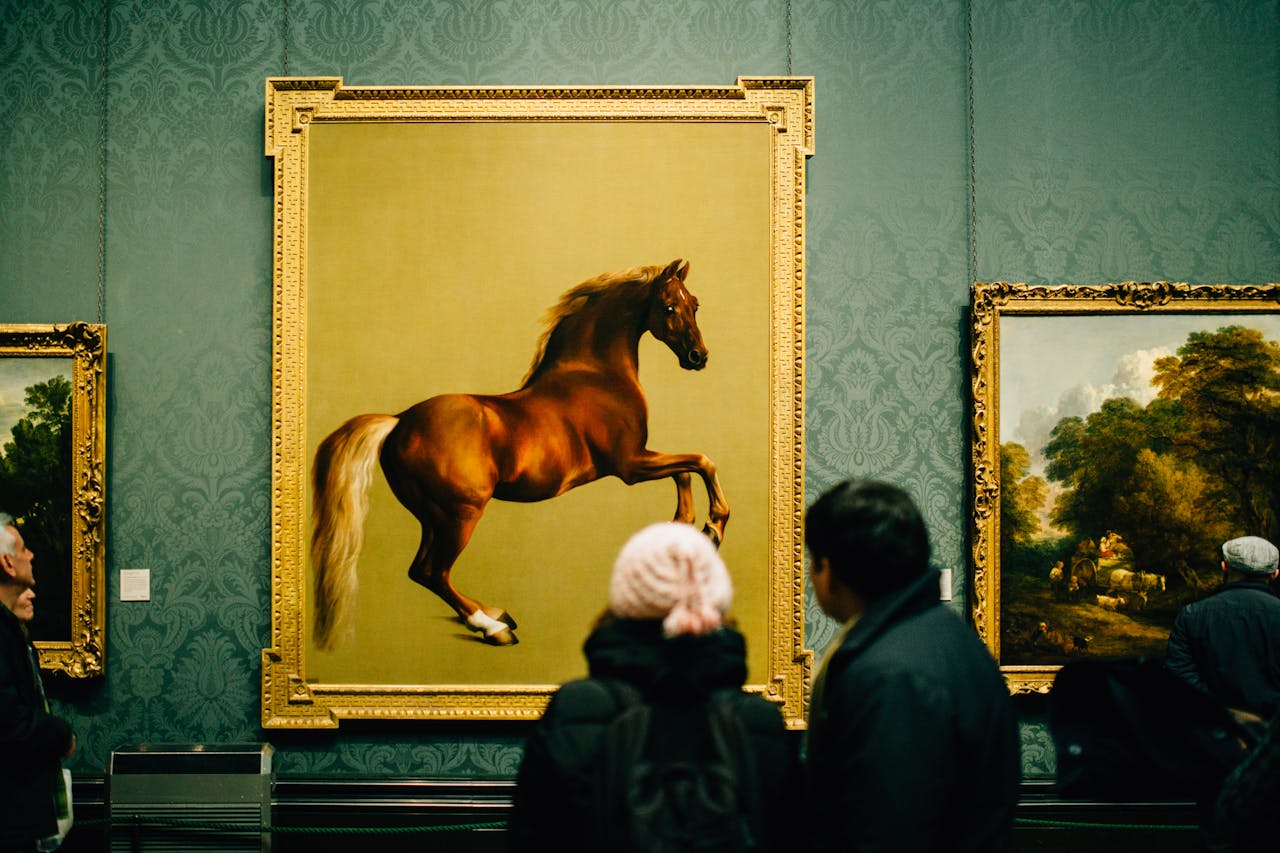 Visiteurs contemplant une peinture classique de cheval dans un cadre doré ornementé.